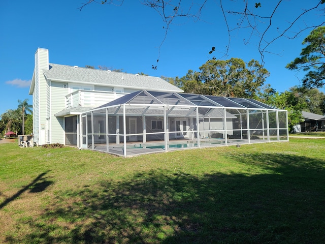 rear view of house featuring a yard and glass enclosure