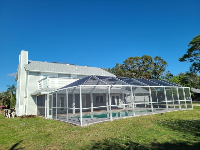 back of property with a yard and glass enclosure