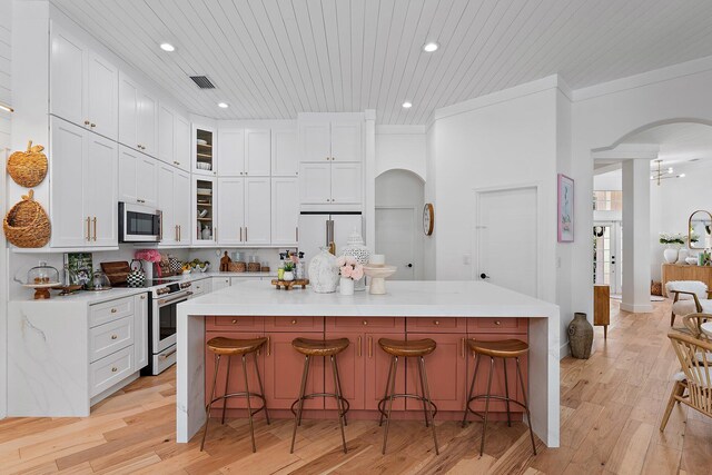 kitchen featuring white cabinets, a kitchen breakfast bar, a center island, and stainless steel appliances