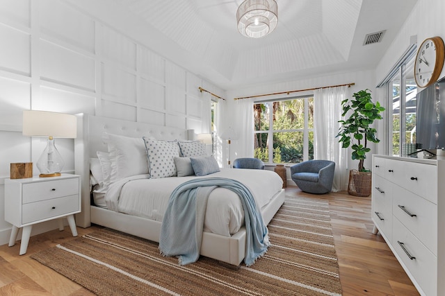 bedroom featuring a tray ceiling and light hardwood / wood-style floors