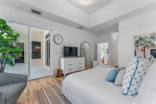 bedroom with access to exterior, light hardwood / wood-style floors, and multiple windows