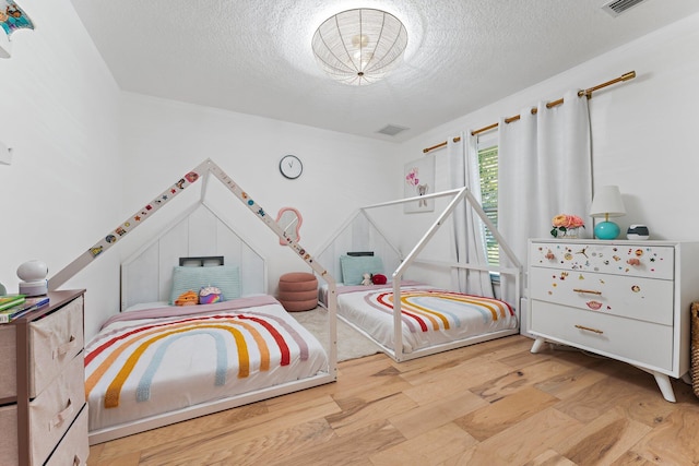 bedroom with a textured ceiling and light wood-type flooring