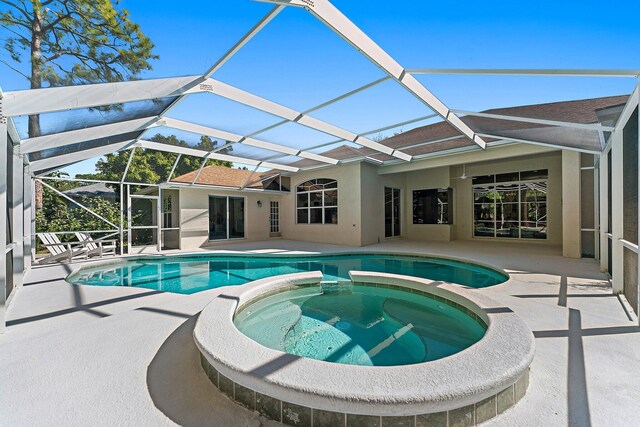 view of pool featuring glass enclosure, an in ground hot tub, and a patio