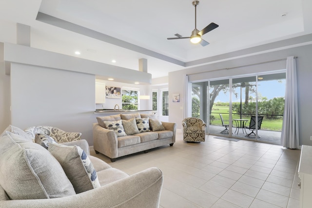 living room featuring light tile patterned floors, a tray ceiling, and ceiling fan