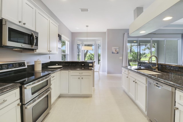 kitchen featuring dark stone counters, sink, white cabinets, and stainless steel appliances