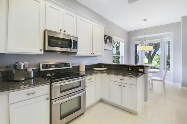 kitchen with appliances with stainless steel finishes, decorative light fixtures, white cabinetry, and dark stone counters