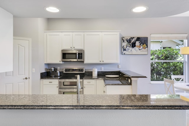 kitchen with white cabinetry, stainless steel appliances, and dark stone counters