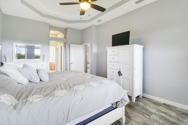 bedroom with ceiling fan and a tray ceiling