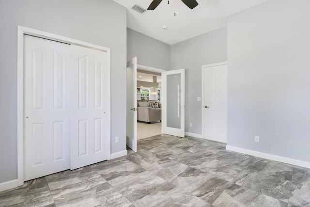 unfurnished bedroom with a towering ceiling, a closet, and ceiling fan