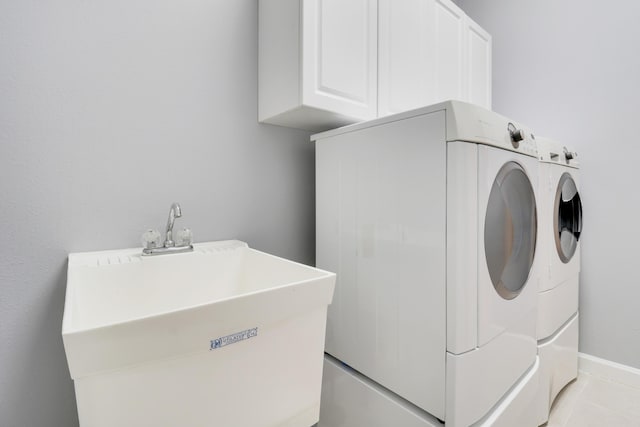 laundry area with washer and clothes dryer, light tile patterned flooring, cabinets, and sink