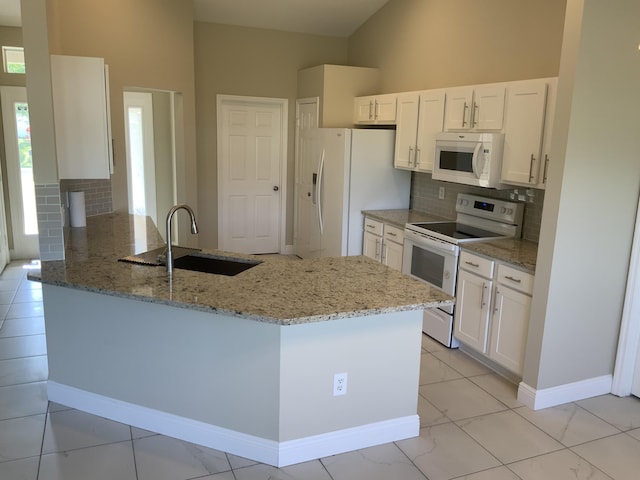 kitchen featuring white cabinetry, a sink, light stone countertops, white appliances, and a peninsula