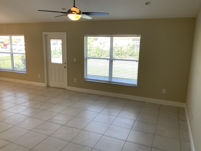 unfurnished room featuring a ceiling fan and baseboards