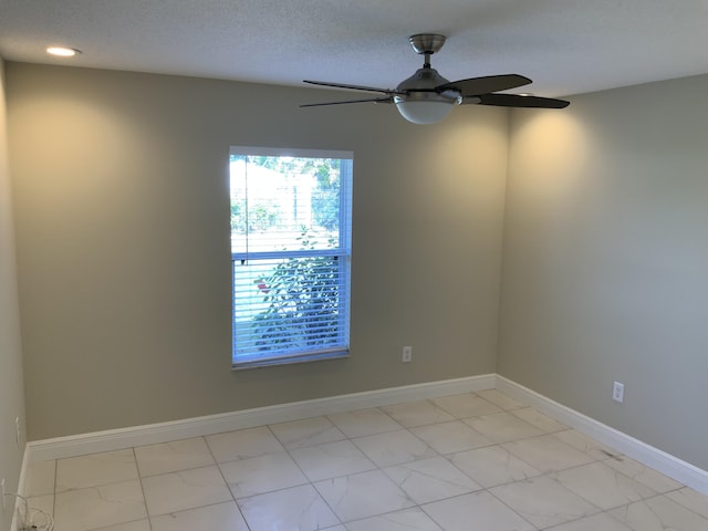 spare room featuring ceiling fan, marble finish floor, a textured ceiling, and baseboards