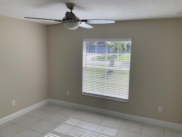 unfurnished room featuring ceiling fan, a textured ceiling, and baseboards