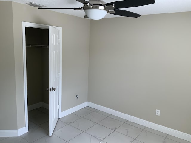 unfurnished bedroom with marble finish floor, a closet, and baseboards