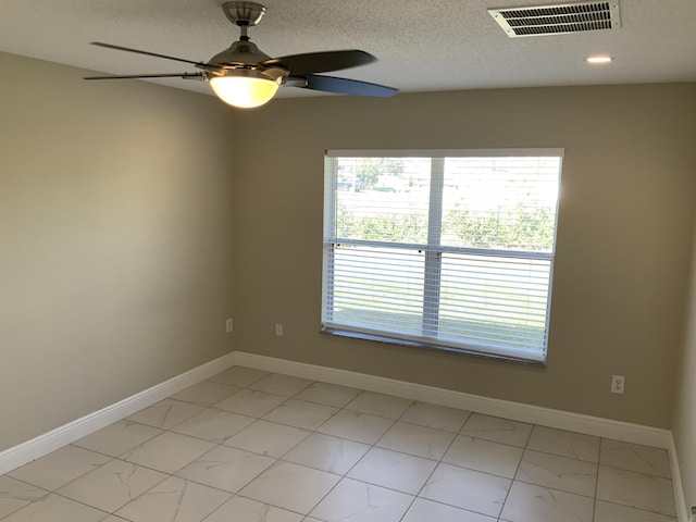 empty room with a ceiling fan, baseboards, visible vents, and a textured ceiling