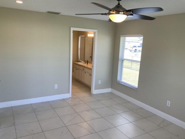 unfurnished bedroom featuring connected bathroom, a sink, visible vents, and baseboards