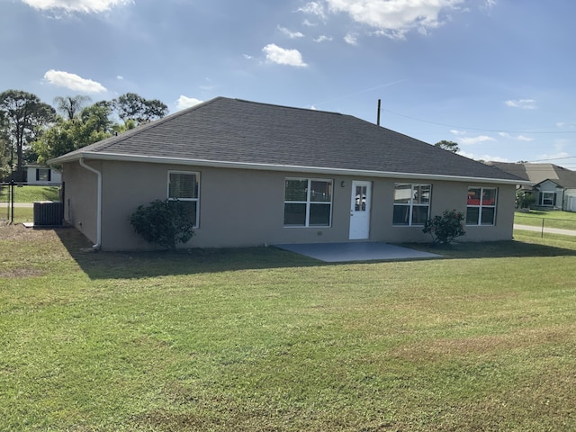 rear view of property featuring a patio, central air condition unit, a yard, roof with shingles, and stucco siding