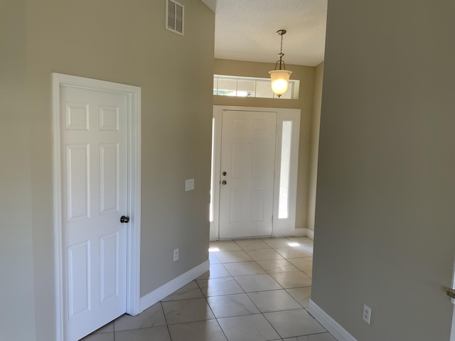 foyer entrance featuring light tile patterned floors, plenty of natural light, visible vents, and baseboards