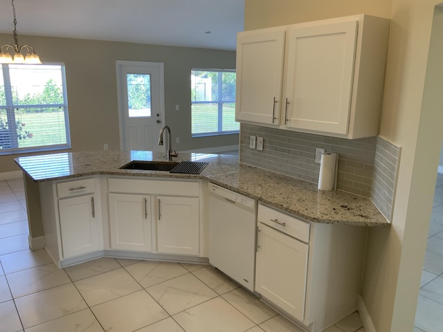 kitchen featuring tasteful backsplash, white dishwasher, pendant lighting, a notable chandelier, and white cabinetry