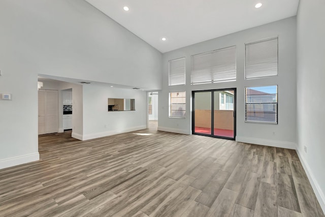 unfurnished living room featuring a towering ceiling and light hardwood / wood-style floors