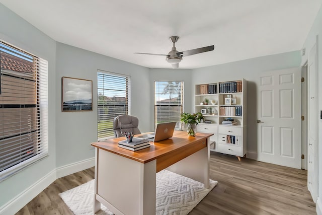 home office with light hardwood / wood-style floors and ceiling fan