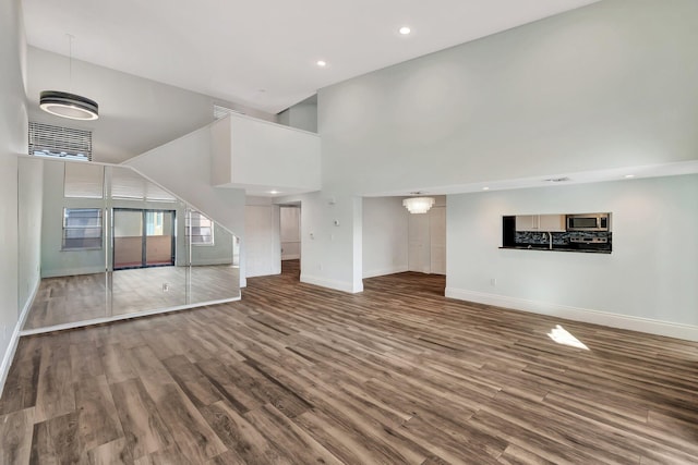 unfurnished living room featuring wood-type flooring and a high ceiling