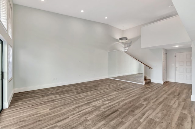 unfurnished living room with light hardwood / wood-style floors and a towering ceiling