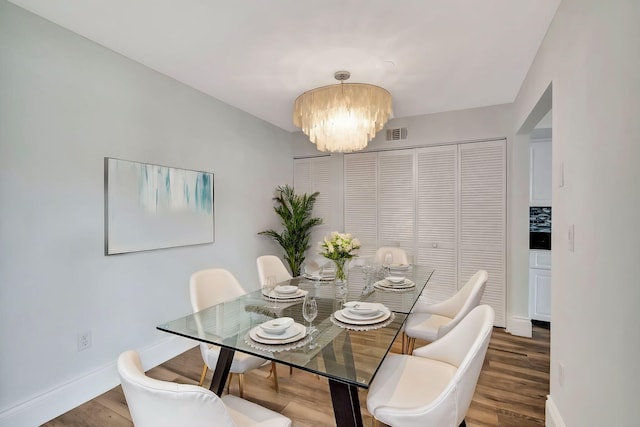 dining space with hardwood / wood-style flooring and a notable chandelier