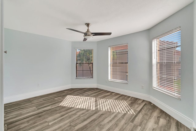 empty room with ceiling fan, hardwood / wood-style floors, and a healthy amount of sunlight