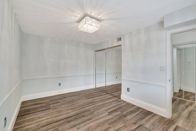 unfurnished room with hardwood / wood-style flooring and a notable chandelier