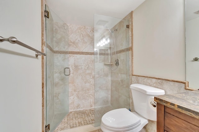 bathroom featuring a shower with door, vanity, tile walls, and toilet