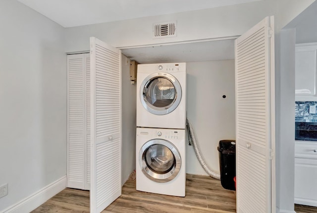 laundry area with hardwood / wood-style flooring and stacked washer and clothes dryer