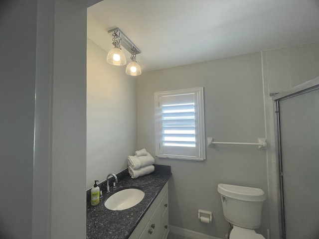 bathroom with vanity, toilet, and a shower with door