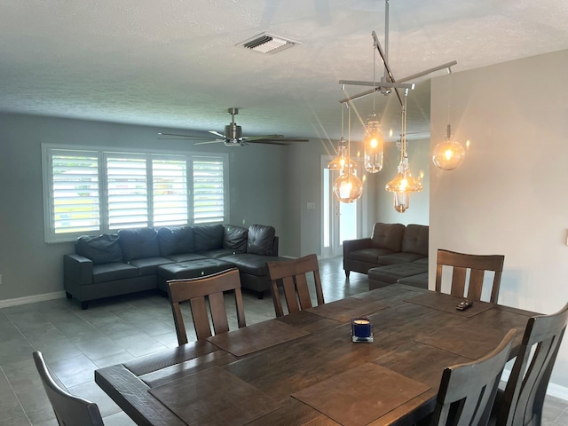 dining space featuring ceiling fan with notable chandelier and a textured ceiling