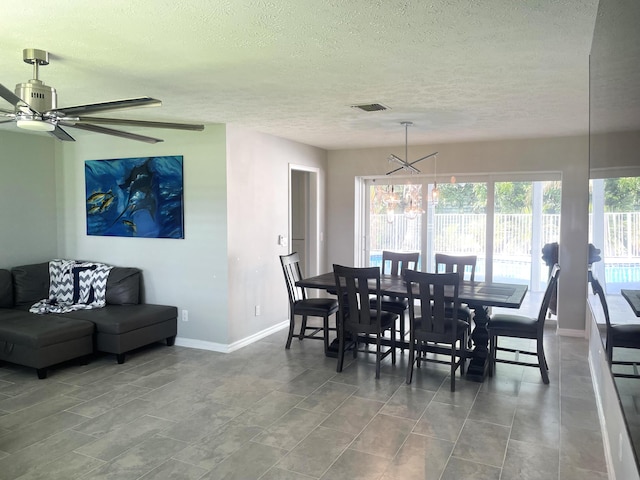 dining space with tile patterned flooring, ceiling fan with notable chandelier, and a textured ceiling