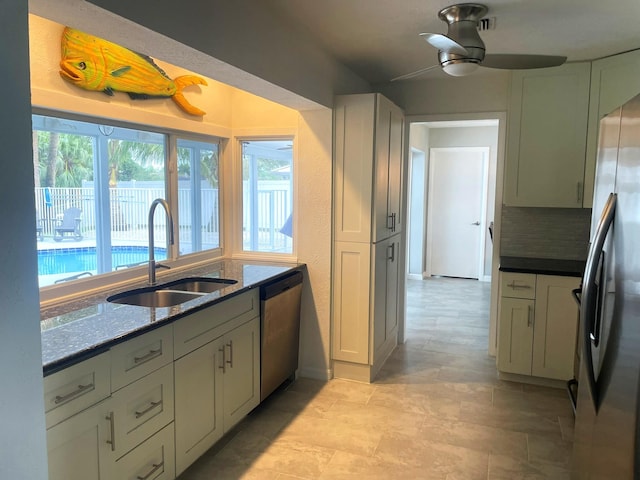 kitchen with ceiling fan, sink, stainless steel appliances, dark stone countertops, and decorative backsplash