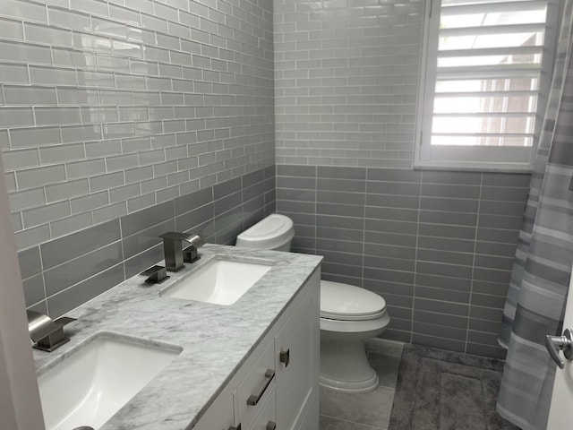 bathroom with curtained shower, vanity, tile walls, and toilet