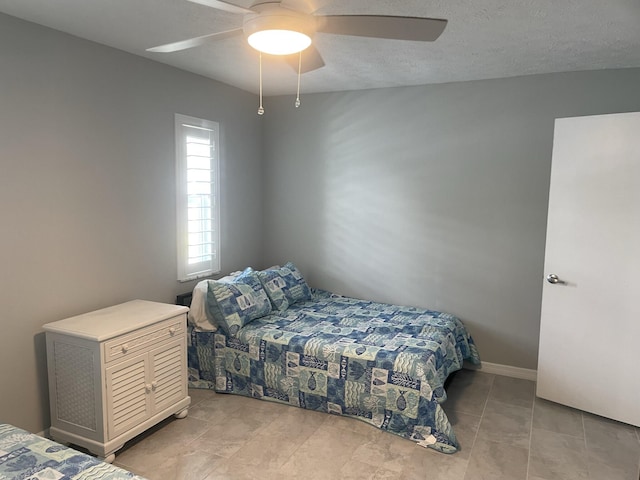 tiled bedroom with a textured ceiling and ceiling fan