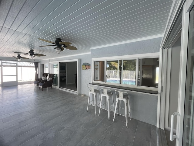 unfurnished sunroom featuring ceiling fan