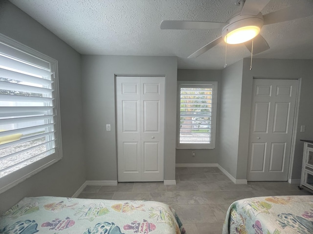 bedroom with ceiling fan, light tile patterned floors, a textured ceiling, and a closet