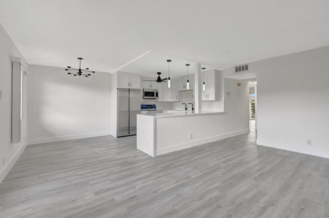 kitchen with kitchen peninsula, stainless steel appliances, sink, pendant lighting, and white cabinets