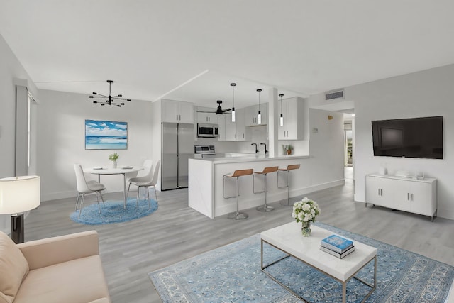 living room featuring light hardwood / wood-style floors, sink, and a chandelier