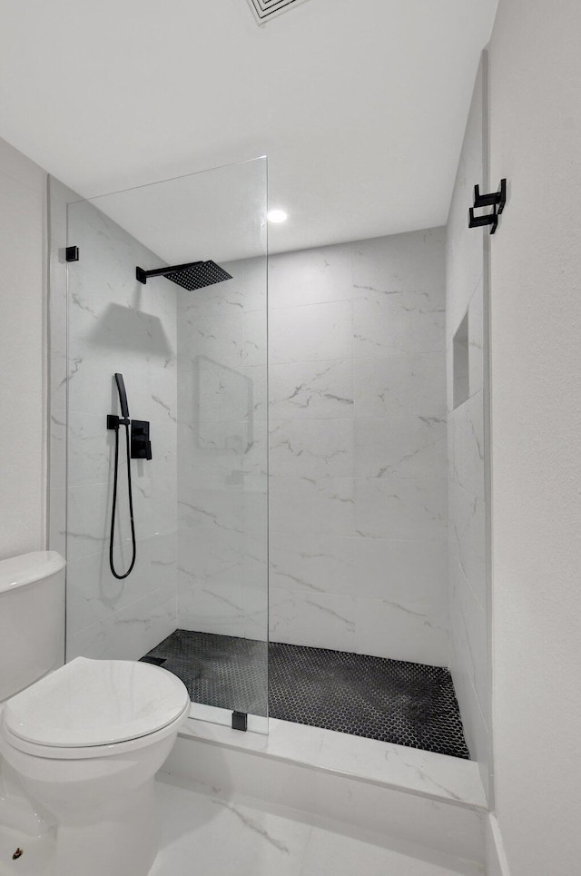 bathroom with a tile shower and toilet