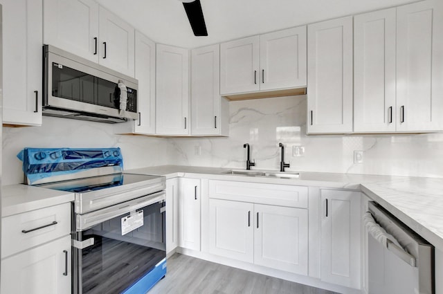 kitchen with white cabinetry, sink, stainless steel appliances, and light wood-type flooring