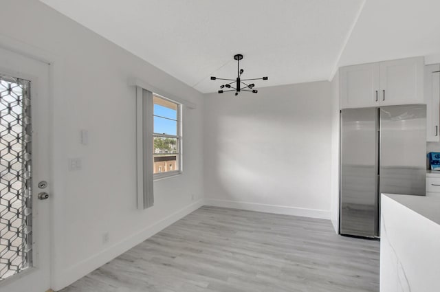 unfurnished dining area featuring light hardwood / wood-style flooring and a chandelier