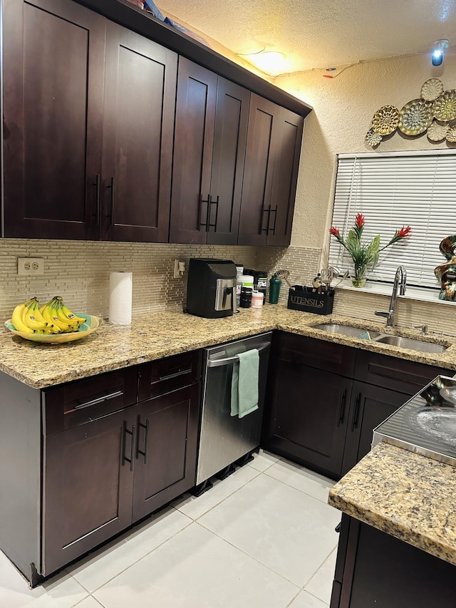 kitchen with dark brown cabinetry, sink, light stone counters, stainless steel dishwasher, and light tile patterned flooring