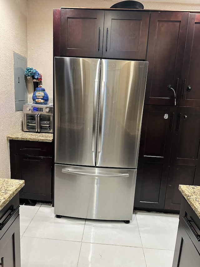 kitchen featuring stainless steel refrigerator, light stone countertops, electric panel, and light tile patterned floors