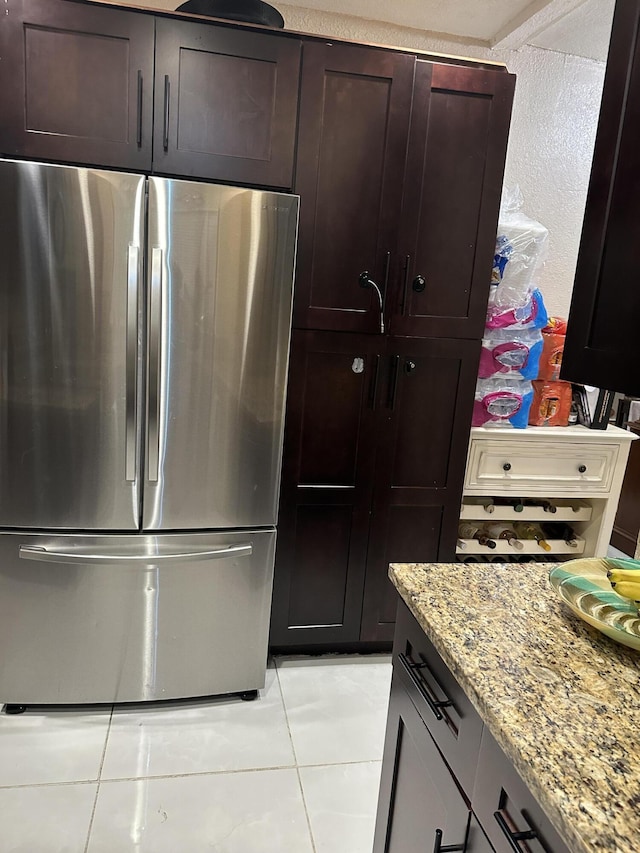 kitchen featuring stainless steel fridge, light tile patterned flooring, and light stone countertops