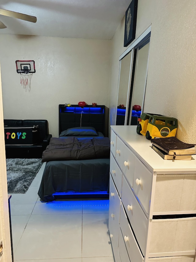 tiled bedroom featuring ceiling fan and a closet